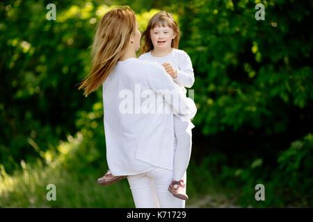 Baby con down sydrome godendo di gioco all'aperto Foto Stock