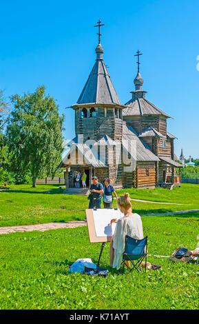 Suzdal, Russia - luglio 1, 2013: il giovane pittore rende il disegno a matita della chiesa medievale di risurrezione nel museo di architettura in legno e p Foto Stock