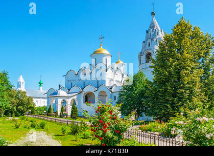 Le chiese medioevali di intercessione il monastero sono circondati da New SCENIC 5 posti e lussureggiante giardino con aiuole di fiori e alberi ombrosi, Suzdal, Russia. Foto Stock