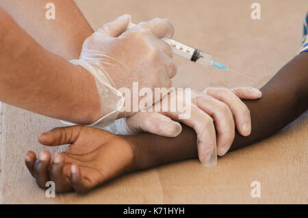Primo piano del ragazzo africano ottenendo un ago di vaccinazione da un medico di volontariato Foto Stock