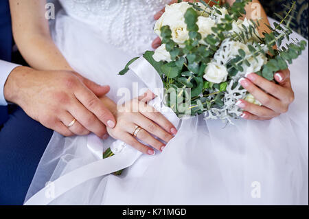 Lo sposo abbraccia la sposa con un matrimonio bouquet di fiori per una passeggiata Foto Stock