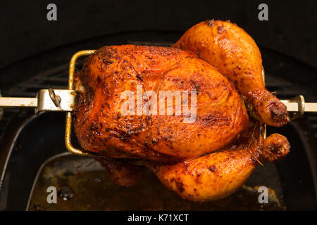 Carbonizzati pollo rotisserie su fiamme aperte in un barbecue. Camera per il testo Foto Stock