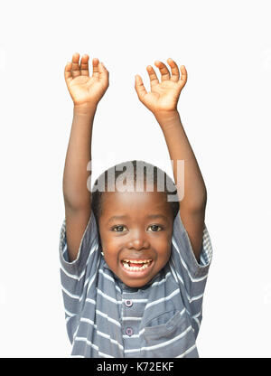 Piccolo ragazzo africano tiene le mani in aria mentre ridendo e sorridente Foto Stock