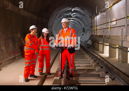 Segretario dei trasporti chris grayling (destra) fissa la clip finale sulla elizabeth liine via, accanto il vice sindaco di Londra per il trasporto val shawcross (sinistra) e ingegnere di pista ellen mcguinness (centro) come il progetto crossrail celebra il completamento della permanente linea di Elisabetta via a Whitechapel, a est di Londra. Foto Stock