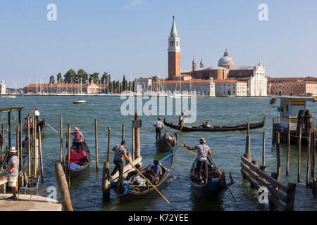 Gondolieri con le loro gondole di fronte a piazza san marco a venezia, Italia. l'isola di san giorgio maggiore è in background. Foto Stock