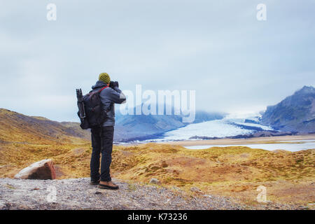 Dolci pendii delle montagne innevate e ghiacciai. splendida Islanda in primavera. Un turista prende le immagini di paesaggio locale Foto Stock