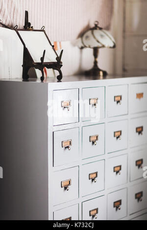 Vintage in legno credenza con un sacco di ripetuti piccoli armadietti in bronzo. telaio e lampada non in alto Foto Stock