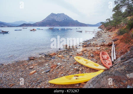 Tre barche sulla spiaggia e barche in mare in background. Foto Stock