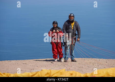 Parapendio in tandem pilota e passeggero preparare il lancio oltre la città costiera di Iquique sulla costa nord del Cile. Foto Stock