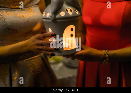 Concezione religiosa. due femmine mani tenendo una candela che brucia nel candelabro. Foto Stock