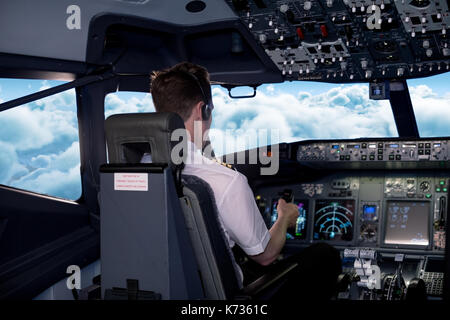 Vista posteriore del giovane maschio Pilota piano di volo dal cockpit Foto Stock