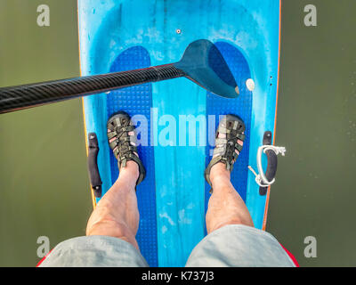 Strette racing stand up paddleboard con una fibra di carbonio racchetta e paddler piedi in acqua sandali - vista superiore Foto Stock