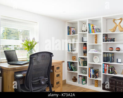 Un piacevole casa ufficio in una casa moderna con scrivania in legno di quercia, laptop e scaffali Foto Stock