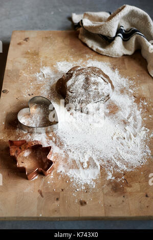 Cucina foto di una spolverata tagliere di legno ed anticato t-asciugamano con crudo, preparati, pasta biscotto tagliate in forme di festa per il natale. Foto Stock