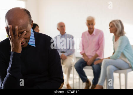 Preoccupato senior maschio con amici in background in classe d'arte Foto Stock