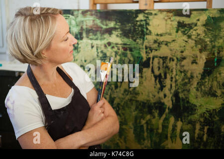 Premurosa donna che guarda la sua pittura in classe Foto Stock