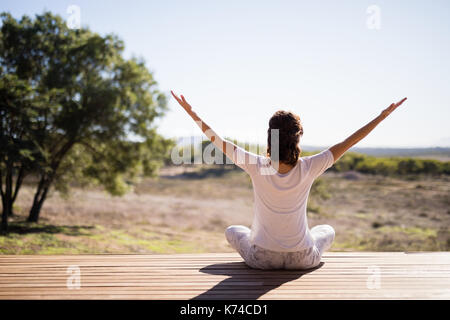 La donna a praticare yoga su tavola in legno in una giornata di sole Foto Stock