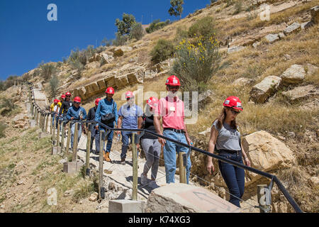 Turisti che visitano la scogliera di Cal Orck’o nel Parque Cretácico / Parco Cretaceo famoso per le sue impronte di dinosauri, Sucre, Bolivia Foto Stock