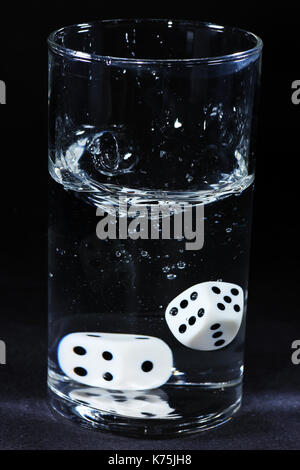 Detail von Spielwürfel mit schwarzen hintergrund im Wasserglas dettaglio di dadi con sfondo nero in un teacup Foto Stock