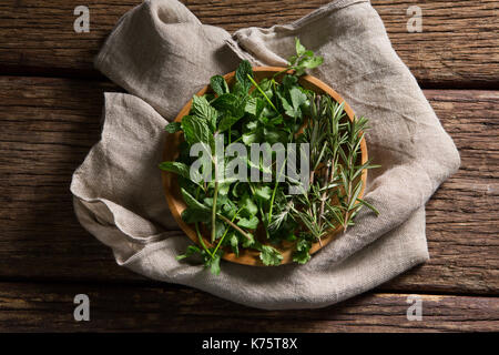 Sovraccarico di erbe aromatiche fresche nella piastra in legno Foto Stock