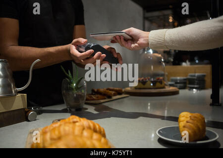 La donna il pagamento fattura tramite lo smartphone utilizzando la tecnologia NFC in ristorante Foto Stock