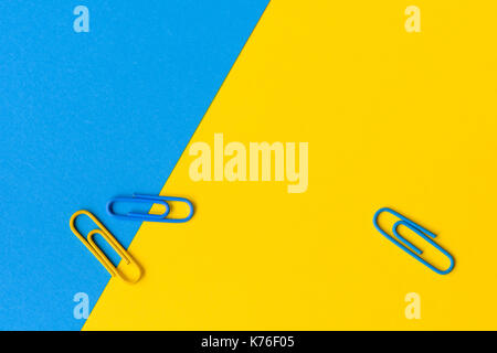 Concetto di ufficio con due blu e uno giallo Graffetta isolata contro un blu e sfondo giallo con copia spazio. Foto Stock