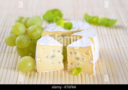 Il francese camembert formaggio a pasta morbida con uve e marjorjam su un cartellone di legno Foto Stock
