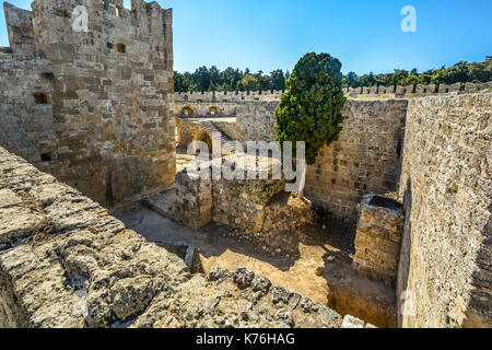 Un disperso, feral cat siede tra le antiche rovine del Castello Di Rodi Rodi in Grecia in una giornata di sole Foto Stock