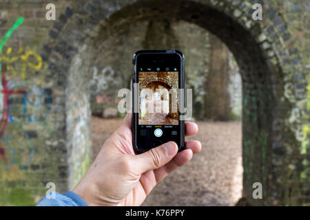 Un maschio per scattare delle foto di un viadotto ferroviario con un iPhone se lo smartphone, REGNO UNITO Foto Stock