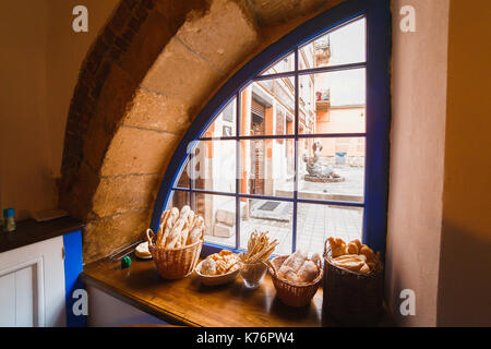 Close-up composizione del pane il cibo nella paglia cestelli disposti sul rustico in legno davanzale. Foto Stock