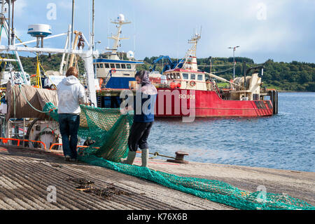 Killybegs, County Donegal, Irlanda. I pescatori in Irlanda il premier pesca porto approfittare di qualche raggio di sole per asciugare le reti da pesca sulla quaysi Foto Stock