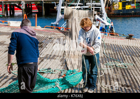 Killybegs, County Donegal, Irlanda. I pescatori in Irlanda il premier pesca porto approfittare di qualche raggio di sole per asciugare le reti da pesca sulla quaysi Foto Stock