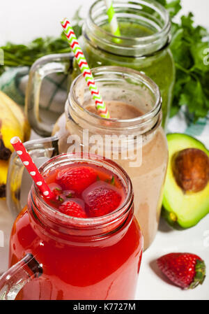 Assortimento di frutta e verdura frullati in vasi di vetro con cannucce su sfondo bianco. Foto Stock