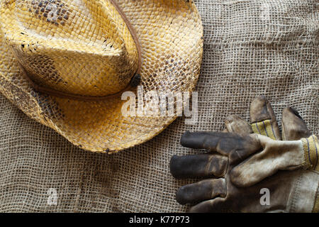 Cappello di paglia e guanti da lavoro su tela Foto Stock