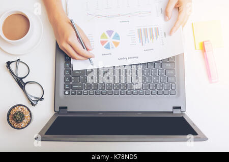 Elevato angolo di visione di un giovane brunette lavorando alla sua scrivania da ufficio con documenti e laptop. imprenditrice lavora su documenti cartacei. Foto Stock
