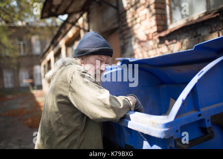 Senzatetto vecchio uomo in cerca di cibo. Foto Stock