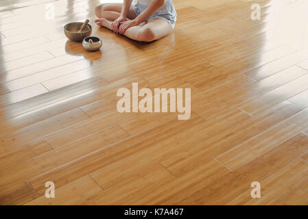 Donna seduta sul pavimento da SINGING BOWLS Foto Stock