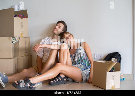 Coppia giovane seduto in casa nuova con scatole di cartone Foto Stock