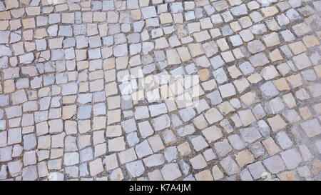 Pavimentazione portoghese, tradizionale e classico stile marciapiede realizzato da molti piccoli pezzi piatti di pietre che può essere visto in strada e strade. Foto Stock