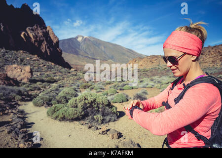 Trail Running donna sul sentiero di montagna guardando sportwatch, controllo prestazioni, cuore di impulso o di posizione GPS nd via. Cross country in esecuzione in Beau Foto Stock