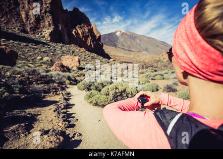 Trail Running donna sul sentiero di montagna guardando sportwatch, controllo prestazioni, cuore di impulso o di posizione GPS nd via. Cross country in esecuzione in Beau Foto Stock