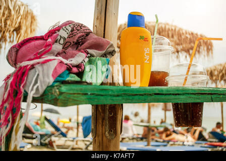 Latte per il corpo su un tavolo sulla spiaggia e bevande fredde Foto Stock