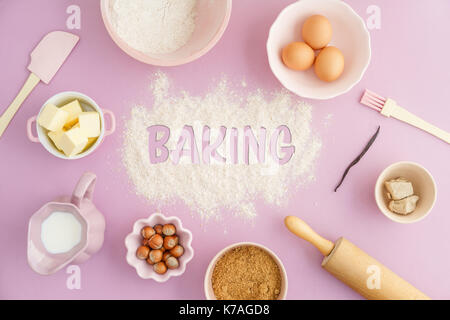 Flatlay raccolta di strumenti e di ingredienti per prodotti da forno su sfondo rosa con la parola scritta di cottura la farina nel centro. Girato da sopra Foto Stock