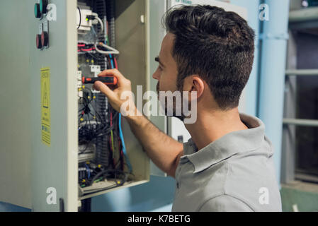 Uomo che lavora in armadio a comando elettrico Foto Stock