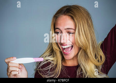 Giovane donna che celebra i risultati di test di gravidanza Foto Stock