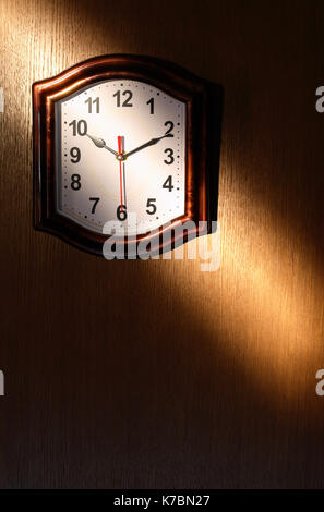 Orologio appeso alla parete di legno con il fascio di luce Foto Stock
