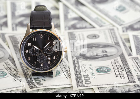 Bello e moderno, orologio da polso in piedi su sfondo costituito da un centinaio di dollari di notes Foto Stock