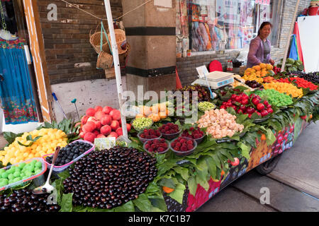 Pressione di stallo di frutta a Suzhou, Cina, Asia. Le piccole imprese a conduzione familiare shop con donna cinese la vendita di prodotti alimentari freschi e frutta in un mercato locale, fiera della città Foto Stock