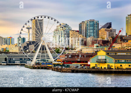 Seattle ruota panoramica Ferris e waterfront. Lo Space Needle in background. oro la luce del tramonto. vista dall'acqua. Foto Stock