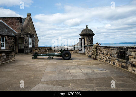 Un cannoniere sta pulendo una pistola o'Clock nel Castello di Edimburgo, in Scozia Foto Stock